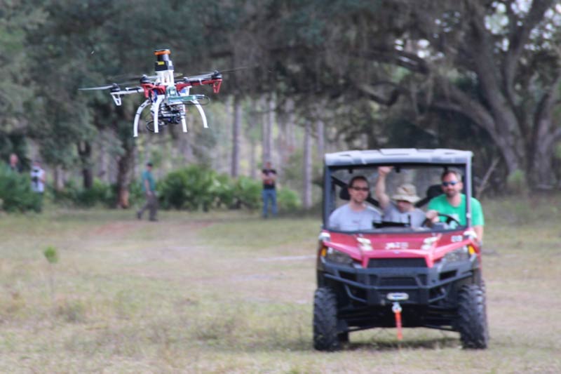 Researchers trail a drone on a test flight outdoors 