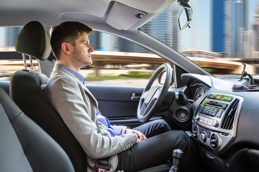 A young man sitting inside an autonomous car